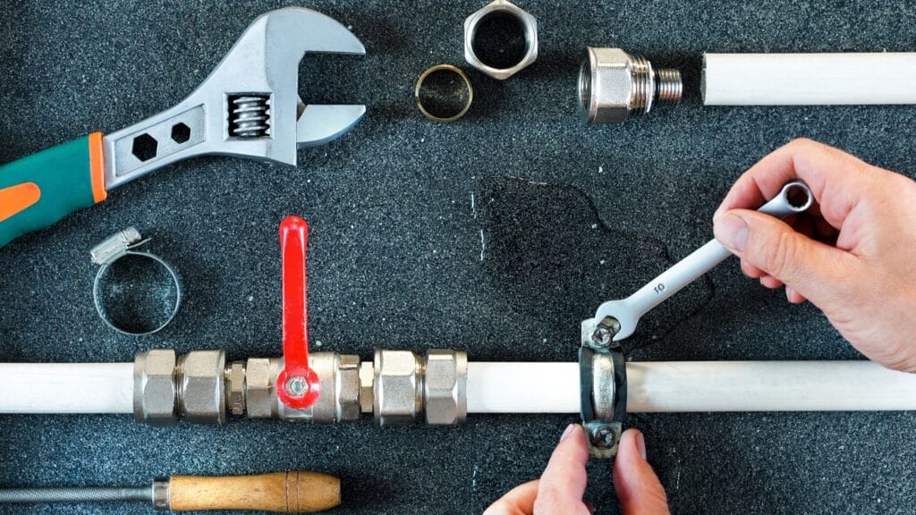 Plumber repairing a pipe valve with an adjustable wrench in Calhoun