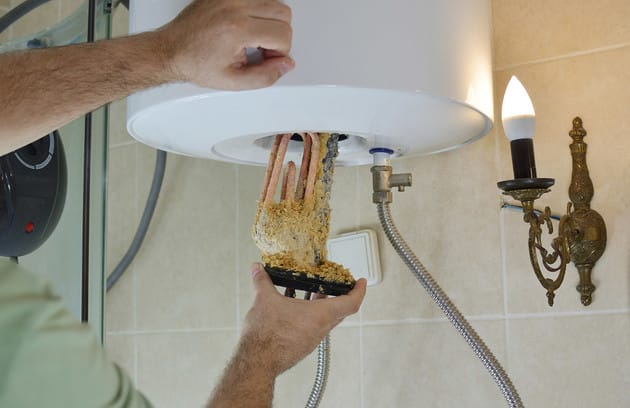 Technician removing mineral buildup from a water heater in Calhoun