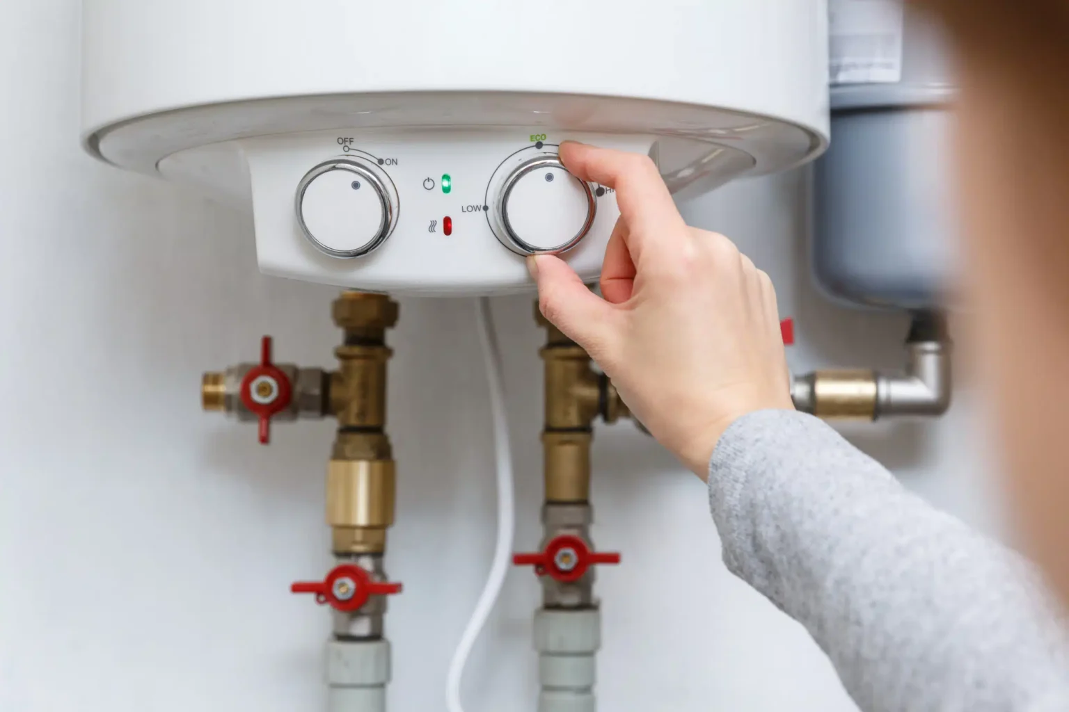 Homeowner adjusting the temperature controls on a water heater in Calhoun